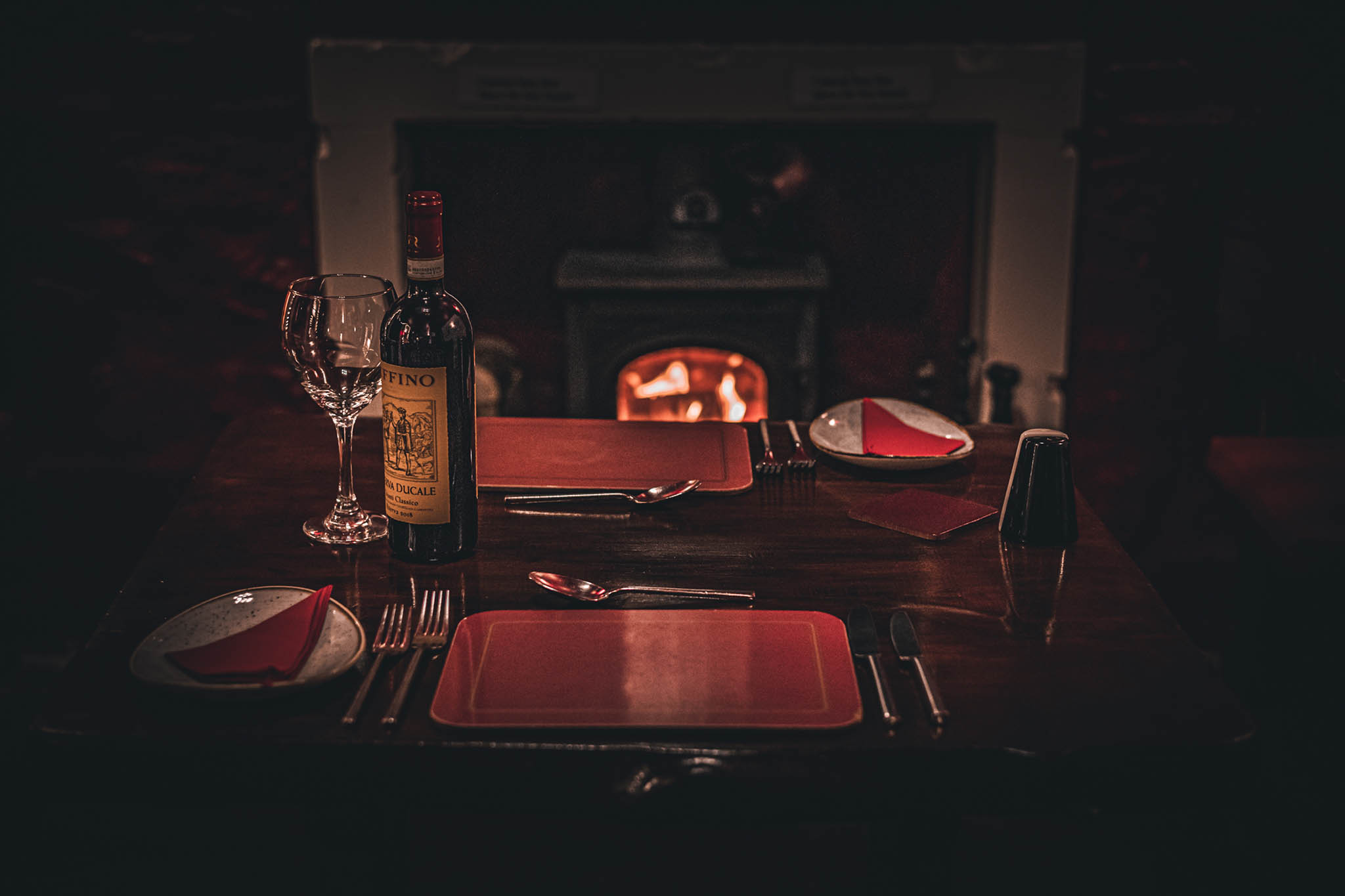 A table set for evening service with a log burner roaring in the background