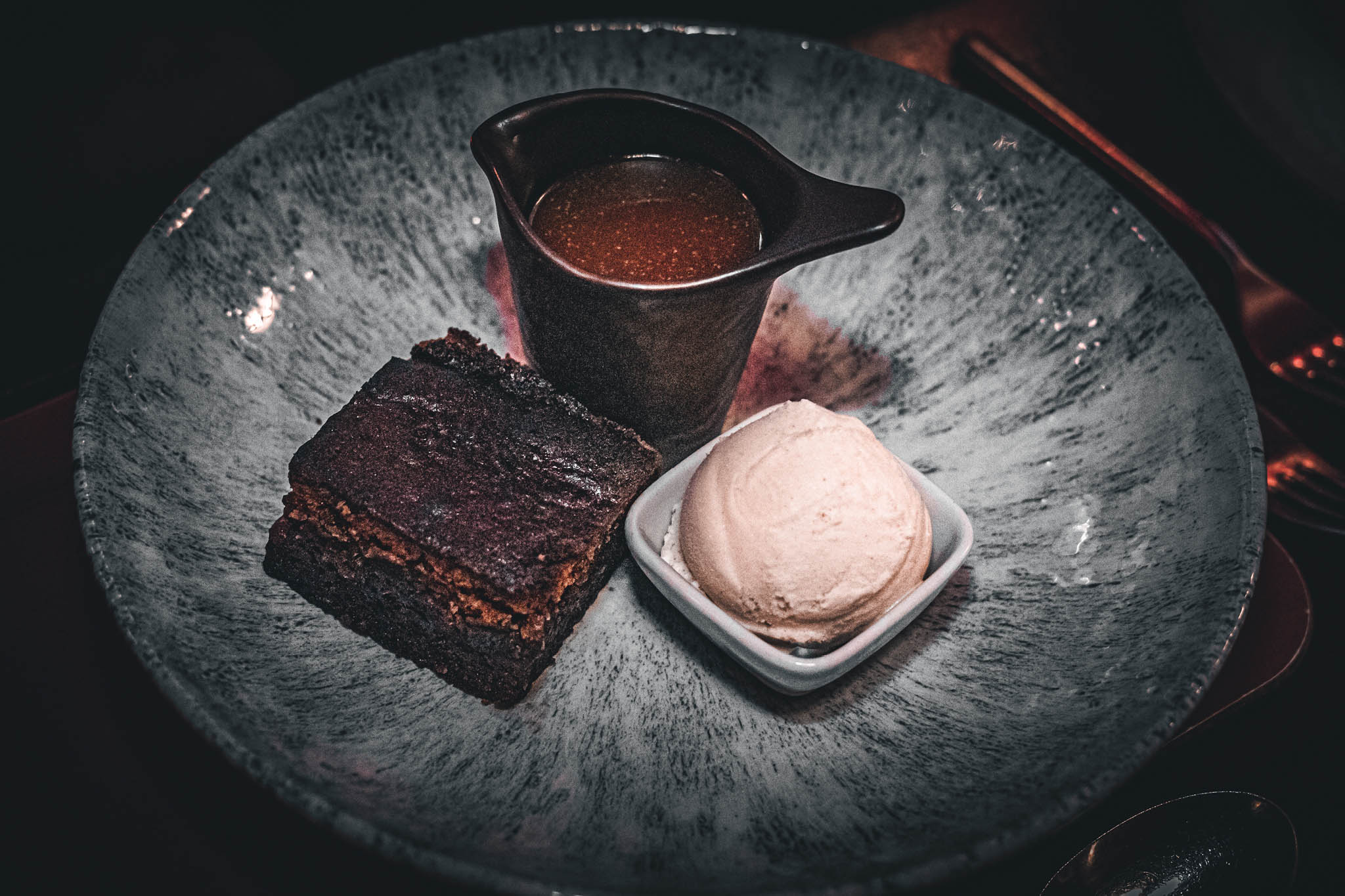 Sticky toffee pudding served with sauce ad ice cream on a blue plate